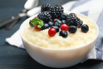 Delicious rice pudding with berries on dark wooden table, closeup