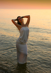 Fototapeta na wymiar Young beautiful woman in white dress enjoying summer time at the beach