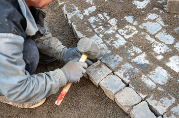 Worker making the pavement of stone blocks