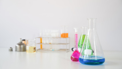 Photo of Scientific equipment and chemistry glassware putting together on white working desk over laboratory white wall as background.