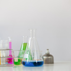 Photo of Scientific equipment and chemistry glassware putting together on white working desk over laboratory white wall as background.