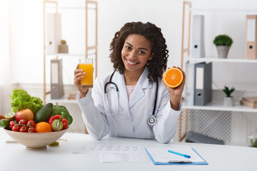 Cheerful female nutritionist holding fresh orange juice