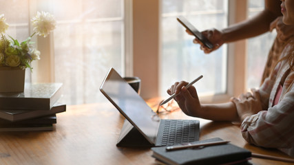 Cropped image of creative woman holding a stylus pen for drawing on computer tablet with keyboard...