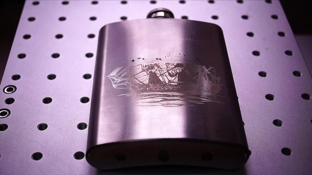 Engraving of a metal flask drawing of a ship by a laser engraver