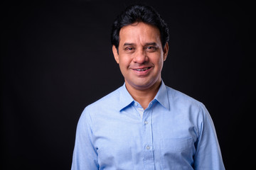 Fototapeta premium Mature handsome Indian businessman against black background