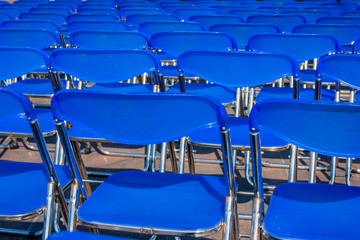 Rows of blue seats in the park with chairs set aside for the concert
