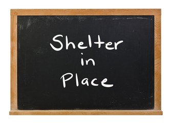 Obraz premium Shelter in Place written in white chalk on a black chalkboard isolated on white