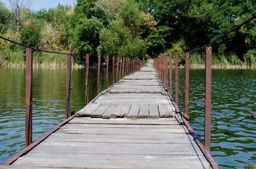 Wooden pantone bridge over a wide river in the Ukrainian village, a view of the forest from the bridge
