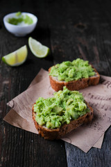  Fresh vegetarian bruscetta with avocado, lime and poached eggs at wooden board on white background