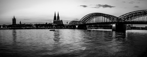 Evening silhouette skyline landscape of the gothic Cologne Cathedral, Hohenzollern railway and pedestrian bridge, the old town and Great St Martin church in Cologne, Germany 