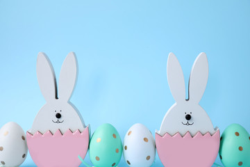 Easter bunnies and painted eggs on light blue background