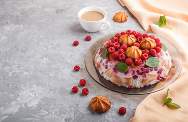 Homemade jelly cake with milk, cookies and raspberry on a gray concrete  background with cup of coffee and orange textile, side view.