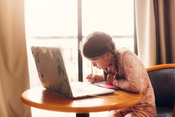 schoolgirl does homework laptop at home,quarantine