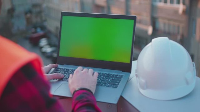 Beautiful background hands man engineer using laptop computer with green screen on balcony helmet worker project occupation builder technology mock-up professional male safety computer slow motion