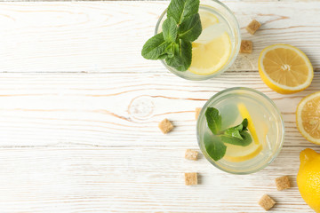Lemonade, lemons and sugar cubes on wooden background, top view