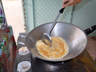 Chef cooking omelet in a hot frying pan.