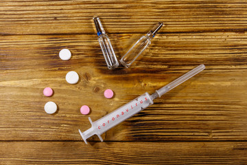 Concept of a prevention and treatment coronavirus. Pills, syringe, ampoules on a wooden background....