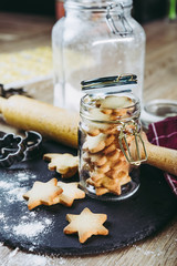 Biscuits sablés dans un pot en verre, rouleau de patisserie farine et emporte pièces pour faire des biscuits	