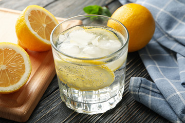 Glass with lemonade and ingredients on wooden background, close up