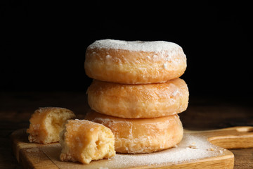 Delicious donuts with powdered sugar on wooden table