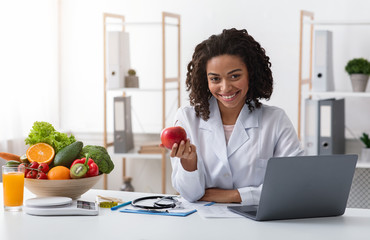 Attractive woman doctor kindly recommending eating fresh fruits