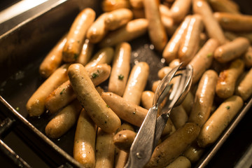 sausage in a pan and tongs.