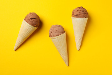 Ice cream in cones on yellow background. Sweet food