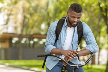 Fitness Tracker. Handsome African Man On Bike Looking At His Smartwatch