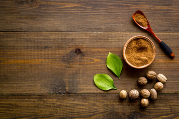 Nutmeg - spices in powder and whole nuts - on wooden background top-down copy space