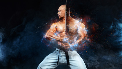 Karate fighter on black background with smoke. Shirtless man samurai with Japanese sword. Fit man...