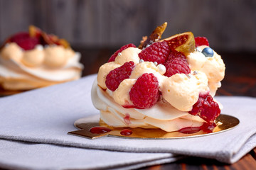 Two dessert Pavlova with raspberries on old brown wooden table. Meringues on a rustic background