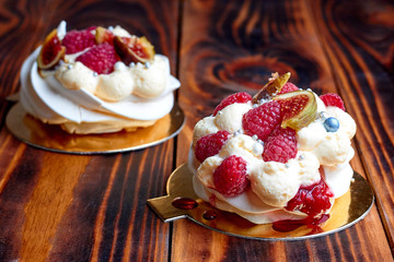 Two dessert Pavlova with raspberries on old brown wooden table. Meringues on a rustic background