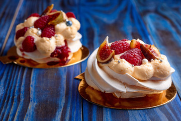 Two dessert Pavlova with raspberries on old blue wooden table. Meringues on a rustic background