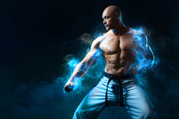 Karate or taekwondo fighter on black background with smoke. Fit man sportsmen bodybuilder physique and athlete. Men's sport motivation. © Mike Orlov