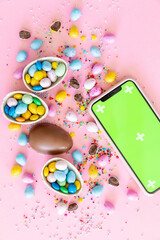 Phone with green screen, stylish easter eggs on pink paper flat lay, space for text. Happy Easter. Greeting card template.	