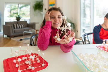 Teenage girl showing the three dimensional structure she built out of marshmallows and toothpicks as part of a homeschool STEM lesson