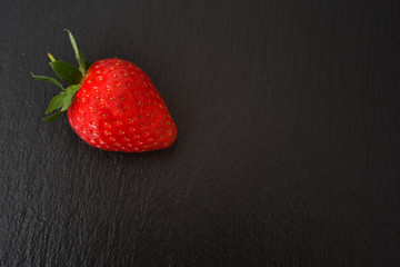 A fresh strawberry against a black background