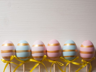 Easter eggs blue and pink on a stick on a wooden background