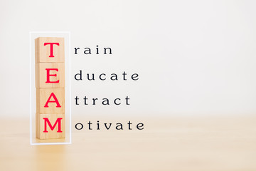 Fototapeta premium Motivation teamwork and team building concept. Wooden block stack up and word TEAM, Train, Educate, Attract, Motivate on wooden table. With copy space for your text.