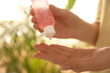 Young woman applying antiseptic gel outdoors, closeup