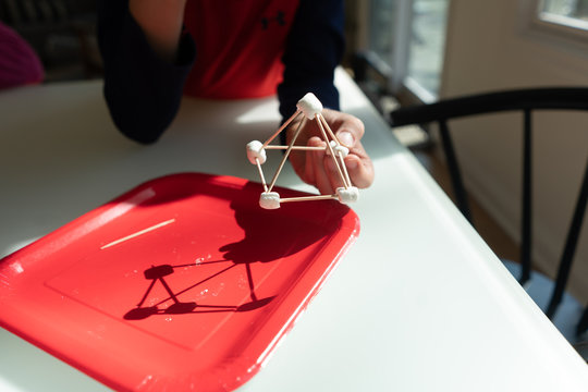 Young boy showing a three dimensional pyramid he built out of marshmallows and toothpicks for STEM lesson