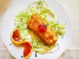 Delicious fresh fried fish with lettuce on white plate