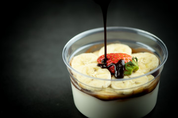 Pour sauce chocolate fresh milk pudding with sliced banana and strawberry
