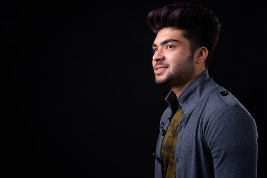 Young handsome Indian man against black background