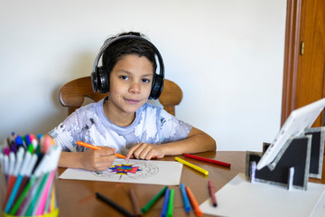 Shot of an adorable boy painting a mandala with his colored markers listening to music on his...