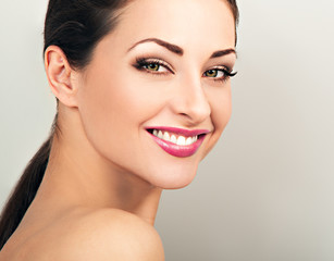 Obraz premium Beautiful woman with healthy clean face skin smiling with toothy smile. Correction eyebrows shape. Dental perfect health. Studio blue background with empty copy space. Closeup