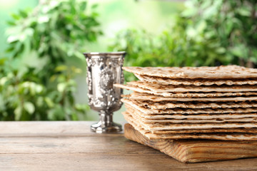 Traditional Matzos and silver goblet on wooden table, space for text. Pesach (Passover) celebration