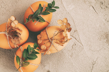 Natural eggs with bunch plant and dried flowers on grey concrete background.
