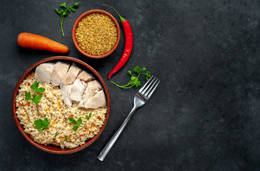 Bulgur with vegetables, chicken fillet on a stone background with copy space for your text. Healthy food