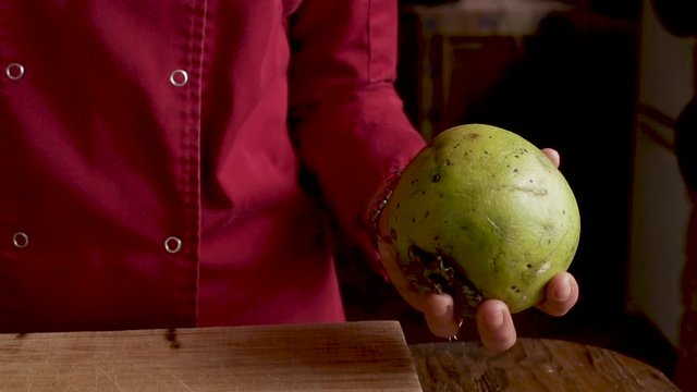 Close up of a chef tossing a black sapote from one hand into another
